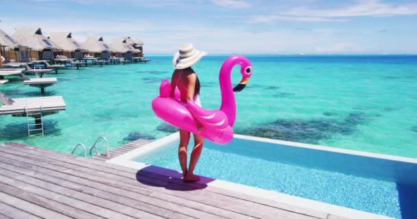 Koncepce dovolené pozadí videa. Cestovní žena v bikinách s nafukovacím růžovým plameňákem plovák hračka u bazénu. Elegantní dáma relaxační těší cestovní dovolenou v resort bazénu — Stock video