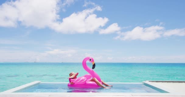 Ταξιδιωτικές διακοπές. Γυναίκα χαλαρώνοντας στην πισίνα από την παραλία ηλιοθεραπεία στο μπικίνι σε φουσκωτό ροζ φλαμίνγκο στρώμα παιχνίδι επιπλέουν. Κορίτσι απολαμβάνοντας πολυτελή τρόπο ζωής στο ξενοδοχείο θέρετρο άπειρο πισίνα — Αρχείο Βίντεο