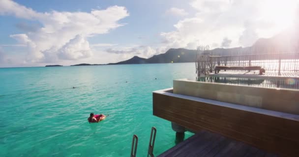 Strandurlauberin entspannt im Pool schwimmen Donut aufblasbaren Ring schwimmt auf türkisfarbenem Ozeanwasser Hintergrund in Französisch-Polynesien Reise Sommer Luxus-Resort auf Bora Bora — Stockvideo