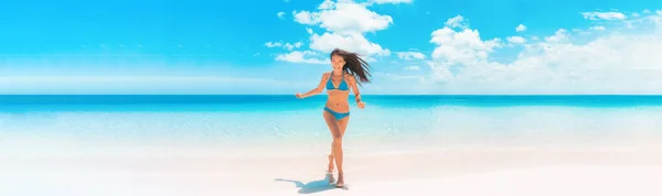 Strand Aziatische vrouw met fit zomer bikini lichaam gelukkig hardlopen genieten Caribische vakantie lachen van vreugde in tropische bestemming banner panorama. Blauwe badmode model genieten van zomervakantie. — Stockfoto