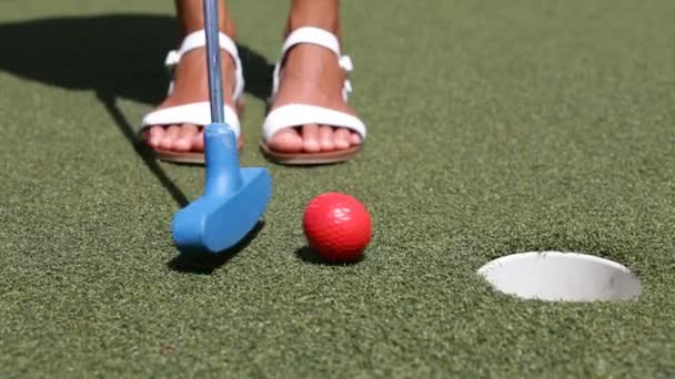ミニゴルフ,ミニチュアゴルフやミニパット-女性は穴にクラブボールを入れて — ストック動画