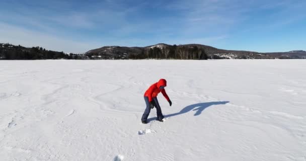 Зимнее веселье. Женщина делает угол снега на замерзшем озере в зимней стране чудес природный ландшафт, Молодая женщина делает снежный ангел. — стоковое видео