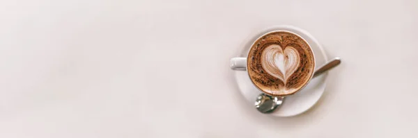 Latte sztuka filiżanka kawy widok z góry na stolik kawiarnia biały tło panoramiczny baner z pianką w kształcie serca wykonane przez barista — Zdjęcie stockowe