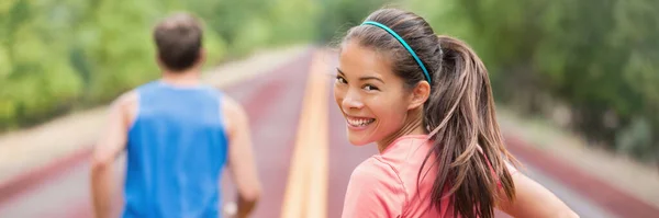 Laufendes Paar beim Straßenlauf im Park-Banner-Panorama-Header. Fit Sportler Läufer Mann und Frau Trainingspartner Freunde Joggen im Sommer im Freien. Asiatisches Mädchen blickt lächelnd zurück — Stockfoto