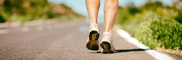 Fitt futó férfi kocogó láb közelkép futó cipő banner panoráma. Sportolók lábak séta az utcán a nyári maraton. — Stock Fotó