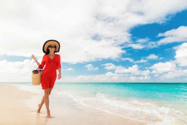 Luxo praia viagem férias elegante senhora andando relaxante em férias com óculos de sol acessórios beachwear, chapéu de sol e saco vestindo vestido vermelho cover-up — Fotografia de Stock