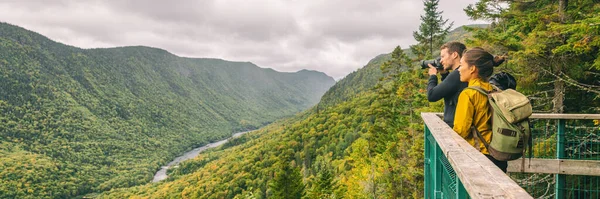 Turyści podróżujący parą robią zdjęcia z aparatem fotograficznym z widokiem na krajobraz górski w jesiennym lesie Parc de la Jacques Cartier, Quebec, Kanada. Tło banera panoramicznego — Zdjęcie stockowe