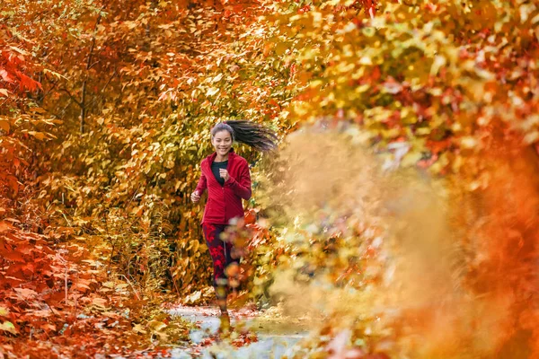 Autunno autunno donna corridore fogliame in esecuzione nei boschi della foresta con bei colori in albero lascia sfondo naturale. Trail corsa atleta asiatico ragazza felice formazione all'aperto — Foto Stock