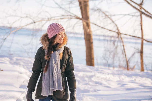 Vinter kvinna promenader ut på skogen promenad i kall utomhus natur flod utanför. Glad asiatisk flicka modell bär ull hatt, halsduk och päls jacka ytterkläder njuter utomhus vinter bakgrund — Stockfoto