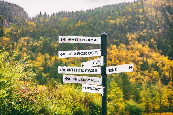 Alasca sinais de rua turística mostrando direções de diferentes cidades turísticas mais próximas destino. Chilkoot, Whitehorse, Juneau, Skagway. Sinal de estrada na cidade de Skagway. — Fotografia de Stock