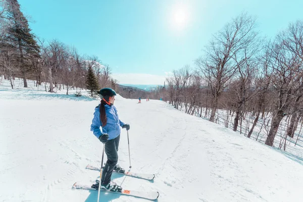 Sciatrice che si prende una pausa durante lo sci in pista. Felice donna attiva asiatica rilassante nella giornata di sole presso la stazione sciistica. Vacanza sportiva invernale — Foto Stock