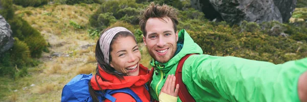 Resor selfie par vandrare tar smartphone bild på utomhus spår vandring i naturen. Aktiva friska glada människor vandring panorama banner. Ungdomar med flera raser — Stockfoto