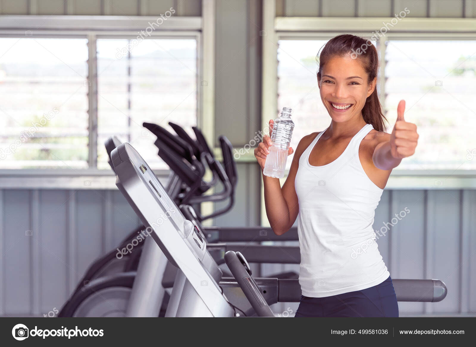 Mulher de ginásio feliz fazendo polegares para cima durante o exercício  cardio na água potável máquina de esteira. Saúde e aptidão fotos, imagens  de © Maridav #499581036