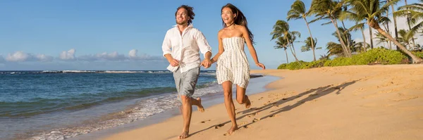 Glückliches Paar beim gemeinsamen Laufen am Strand. Junge multiethnische Menschen, die sich während des Sonnenuntergangs im Tropenurlaub amüsieren. Sommerreiseziel — Stockfoto