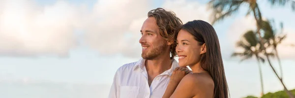 Avkopplande multiracial par tittar på solnedgången på stranden semester banner. Porträtt av asiatisk kvinna, vit man tillsammans njuter av att titta på himlen kopiera utrymme — Stockfoto