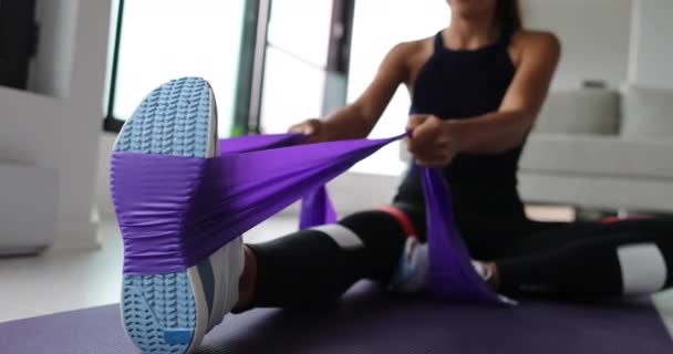 Exercício de resistência em casa. Mulher fazendo treino de pilates usando alça elástica puxando com braços para treinamento de ombro no tapete de ioga dentro de casa. — Vídeo de Stock