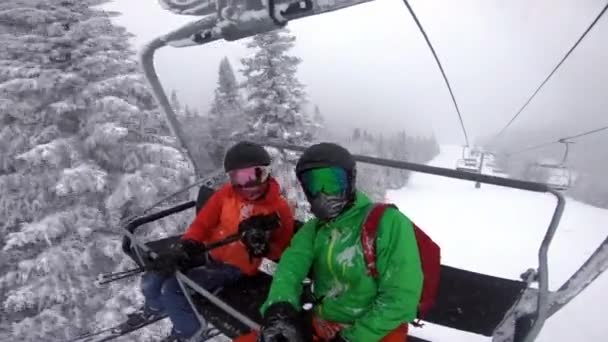 Лыжные каникулы - Пара на лыжном подъемнике делает селфи видео. Концепция зимних каникул. Катание на лыжах по снежным склонам в горах, Люди веселятся в снежный день - Зимние виды спорта на свежем воздухе. — стоковое видео