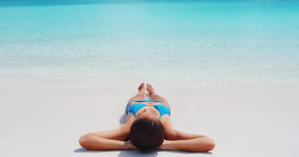 CINEMAGRAPH SEAMLESS LOOP VIDEO: Strandreisende Frau sonnt sich entspannt im Liegen am perfekten paradiesischen Strand. Entspannte Frau im blauen Bikini am Strand im Sommer Idyllischer Urlaub im Luxus-Inselresort — Stockvideo