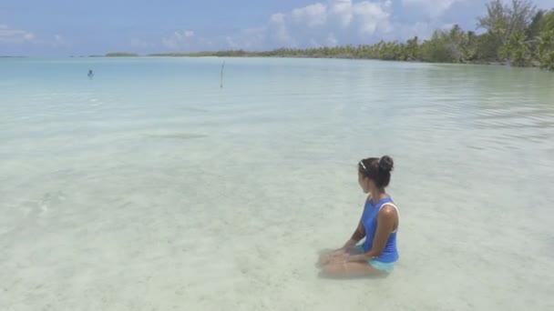 타히티의 산호초 초호에서 산호초 상어 옆에 앉아 있는 폴리네시아의해 변 여성 — 비디오