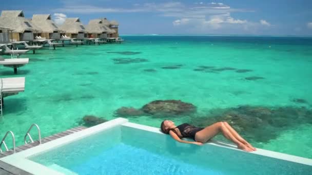 Hotel de luxo Tahiti férias swimsuit modelo mulher relaxante banhos de sol por piscina — Vídeo de Stock
