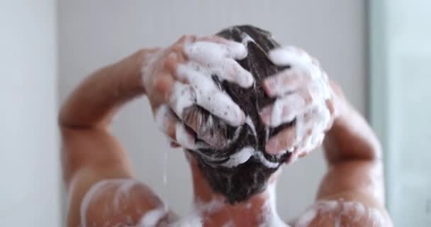 Homem tomando um chuveiro lavar o cabelo com shampoo produto debaixo de água — Vídeo de Stock