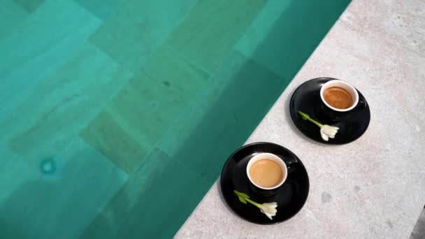 Café en tazas de café expreso para dos personas en el lado de la piscina de lujo de vacaciones — Vídeo de stock