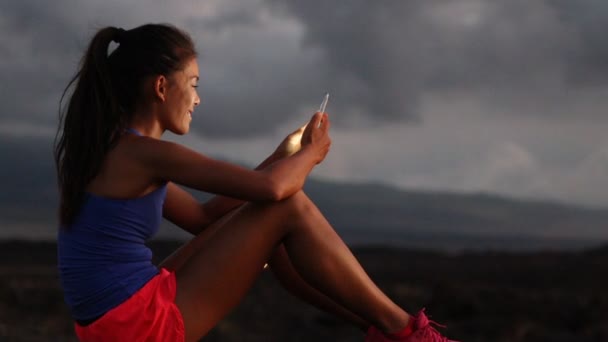 亚洲妇女使用智能手机观看夜间运行的健身跟踪应用程序 — 图库视频影像