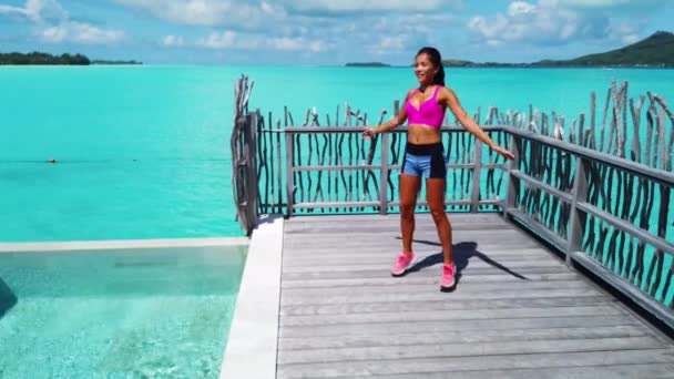 높이뛰기를 하는 건강 한 여자가 열 대의 낙원에서 놀라운 환경에서 스타 점프대를 타고 밖에서 운동을 하고 있다. — 비디오