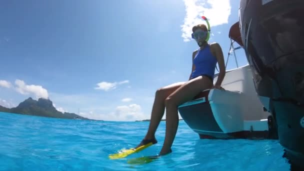 Buceando desde el barco en Bora Bora, Tahití, Polinesia Francesa. Mujer saltando en aguas cristalinas con equipo de snorkel en laguna de arrecifes de coral con Bora Bora hito Monte Otemanu en el fondo — Vídeos de Stock