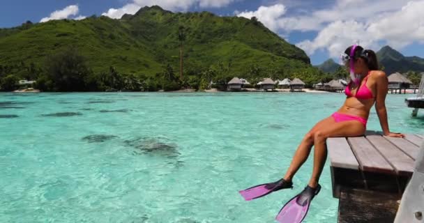 Moorea, Tahiti 'deki lüks bir tatil beldesinin su altı bungalov balkonunda dinlenen mutlu şnorkel kız. Şnorkelle yüzen spor aktivitesi bikinili kadın plaj cenneti tatilinde güneşleniyor. Seyahat yaşam tarzı — Stok video