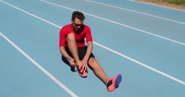 Atleta sprinter preparándose para correr atando cordones de zapatos en pista de atletismo del estadio — Vídeo de stock