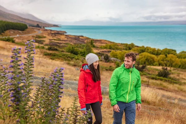 Viajes a Nueva Zelanda: un par de turistas que caminan en la naturaleza con vistas al lago Pukaki cerca de Aoraki, también conocido como Monte Cook, en el mirador de Peters, un famoso destino turístico en Nueva Zelanda —  Fotos de Stock