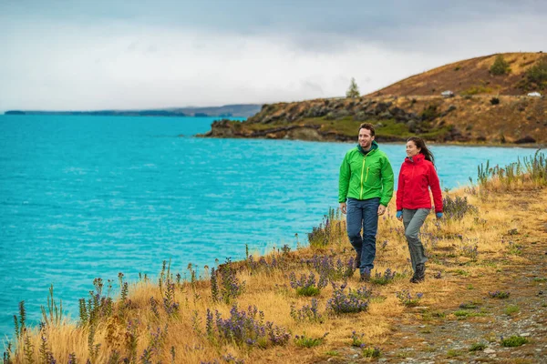 Personas activas en actividades al aire libre. Pareja de turistas senderismo en la naturaleza con vistas al lago Pukaki cerca de Aoraki aka Monte Cook, un famoso destino turístico en Nueva Zelanda —  Fotos de Stock