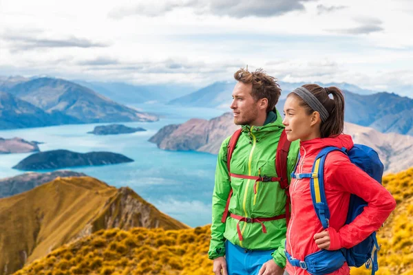 Caminhadas casal wanderlust aventura e conceito de viagem com caminhantes relaxante olhando para a vista. Caminhadas casal tramping up famosa caminhada para Roys Peak em South Island, Nova Zelândia — Fotografia de Stock