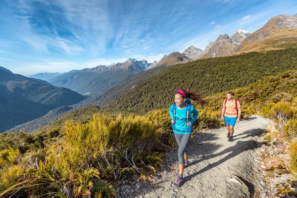 Caminhadas casal andando na trilha em Routeburn Track durante o dia ensolarado. Caminhantes masculinos e femininos estão pisando em Key Summit Track. viajar no Parque Nacional de Fiordland, na Nova Zelândia — Fotografia de Stock