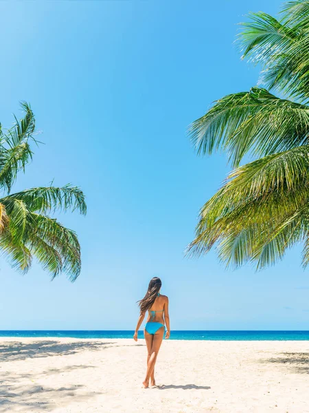 Turista de vacaciones en la playa disfrutando de un viaje en crucero por el Caribe caminando en bikini sobre fondo azul vertical y palmeras, mujer feliz relajándose en Barbados —  Fotos de Stock