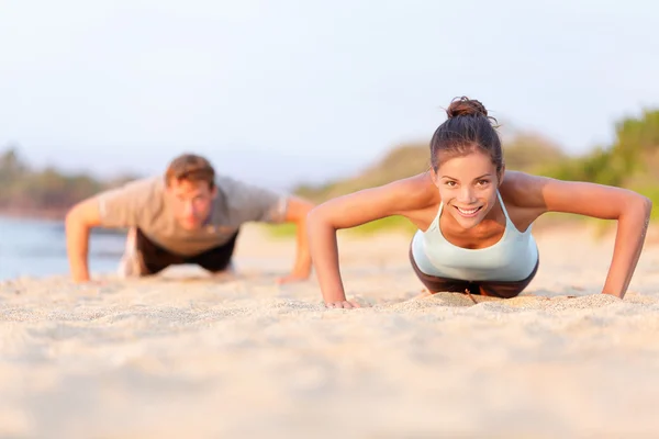 Menschen machen Liegestütze am Strand — Stockfoto