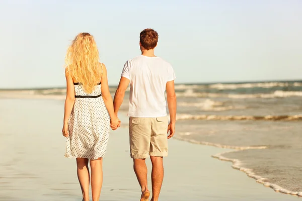 Casal caminhando ao pôr do sol pelo mar — Fotografia de Stock