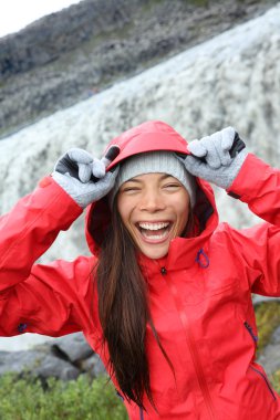 Woman laughing in raincoat near Dettifoss waterfall clipart