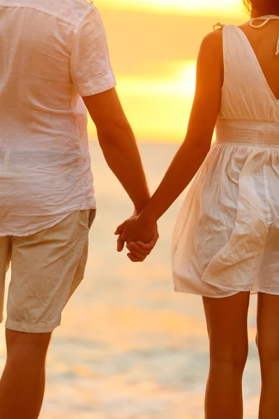 Paar bedrijf handen op strand bij zonsondergang — Stockfoto