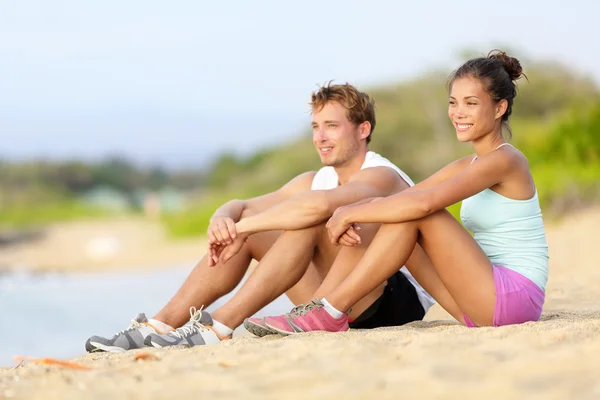 Läufer sitzen vor dem Lauf am Strand — Stockfoto