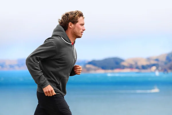 Hombre corriendo con capucha cerca del agua — Foto de Stock