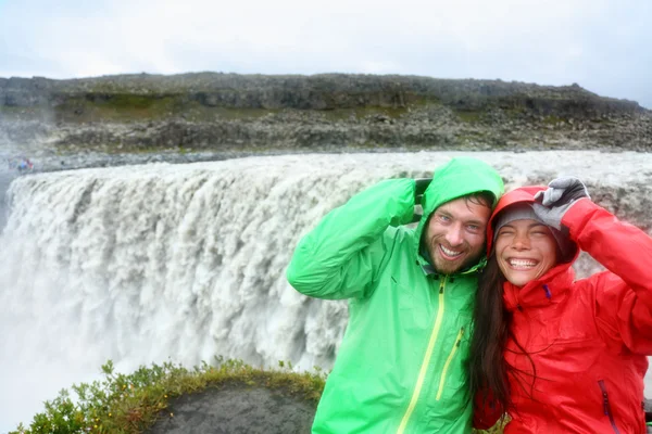 Pár v pláštěnky poblíž vodopád Dettifoss — Stock fotografie