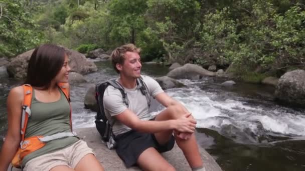 Caminantes pareja relajándose por el río — Vídeo de stock