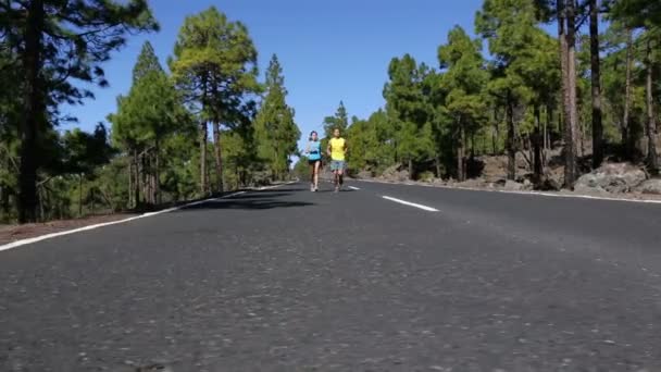 Man en vrouw joggen op bergweg — Stockvideo