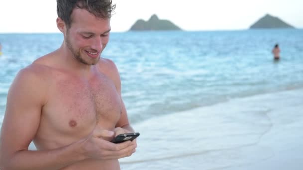 Hombre usando el teléfono inteligente en la playa — Vídeo de stock