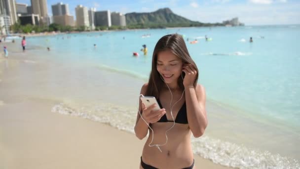 Жінка на пляжі слухає музику — стокове відео