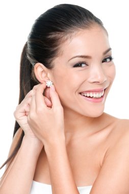 Woman putting on diamond earrings clipart