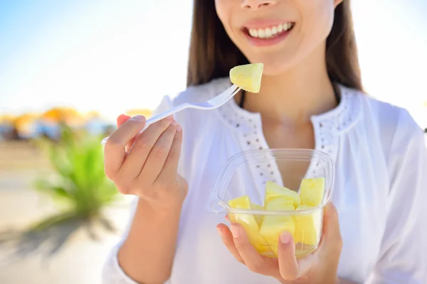 Frau isst geschnittene Ananas — Stockfoto