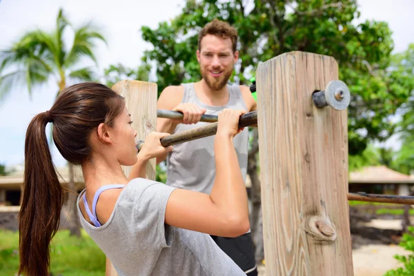 Fitness couple training on chin-up bar
